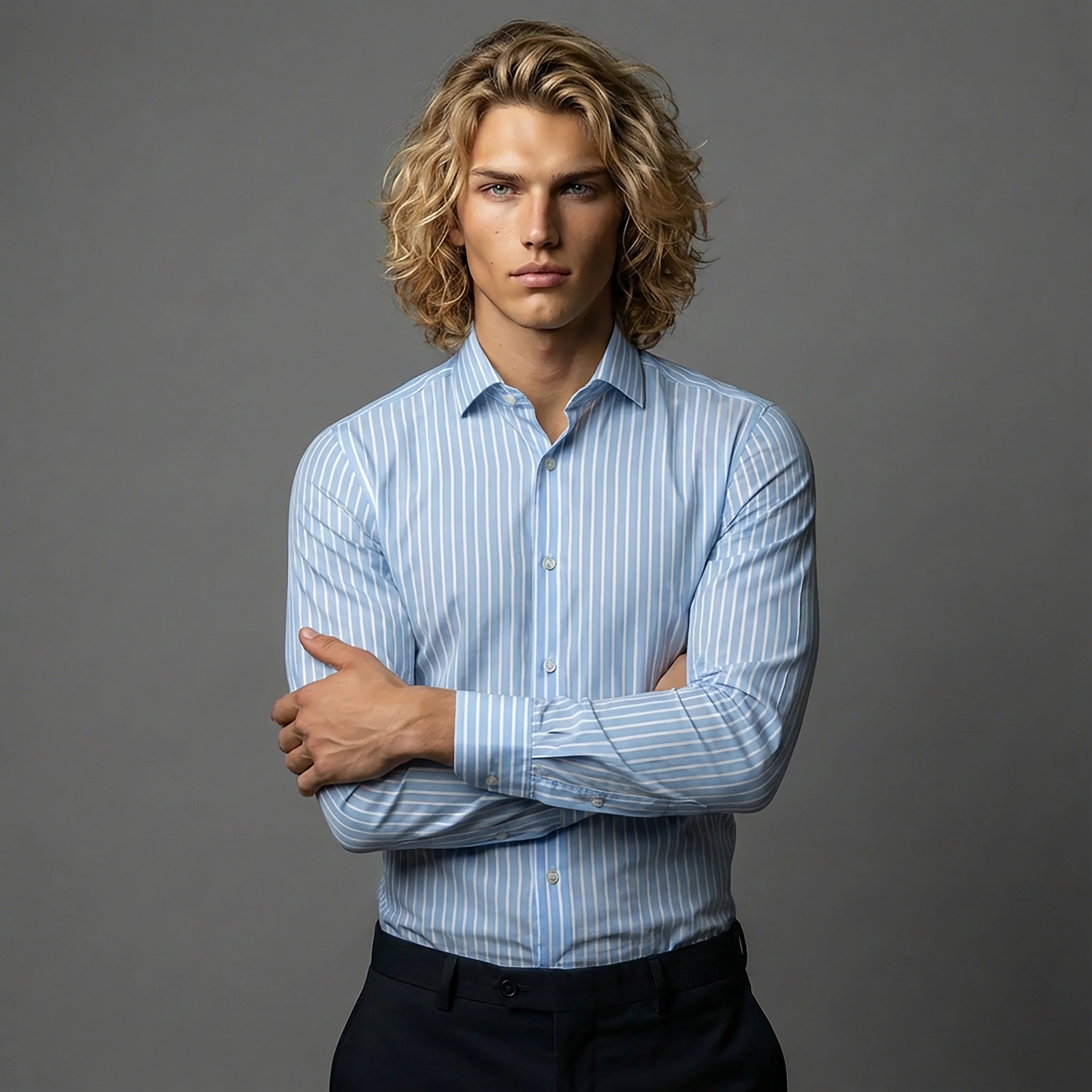 Man in DGMAH light blue striped dress shirt with long sleeves, posing against gray background